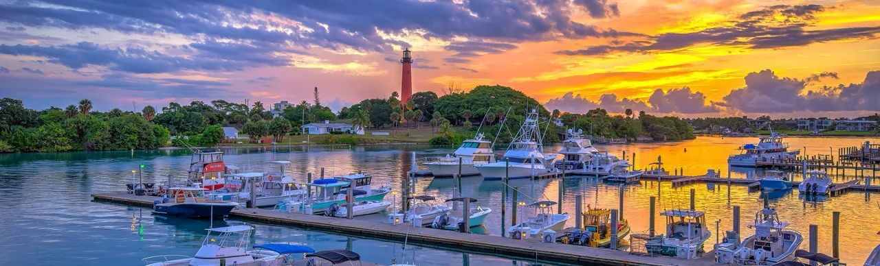 Scenic View of Jupiter Inlet Lighthouse Overlooking Boats Docked in the Tranquil Waters of the Bay at Sunset, Exemplifying Jupiter's Blend of Natural Beauty and Outdoor Lifestyle
