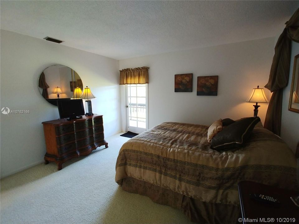 Guest bedroom with private balcony overlooking the golf course and ponds.
