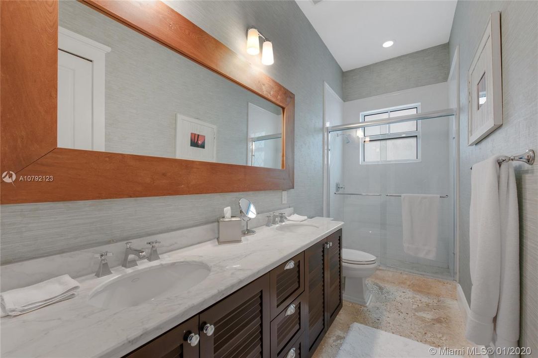 Jack & Jill Bathroom with limestone flooring, extra high ceiling, and twin sinks.