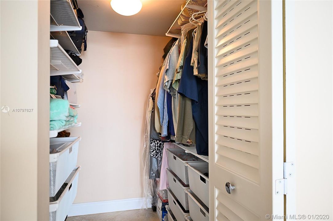 Large walk-in master bedroom closet with drawers and shelving for plenty of storage needs