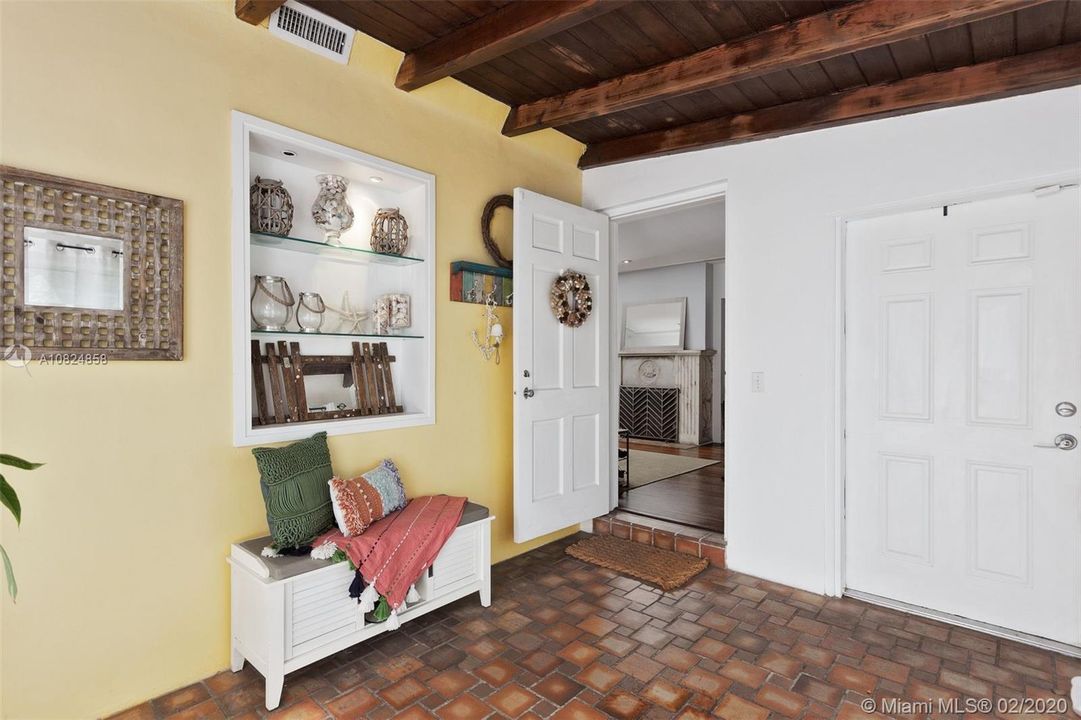 Original cracked tile floor and open beamed ceiling entryway.