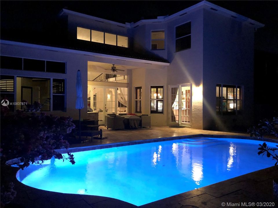 View of back of house at night time with changing pool light feature