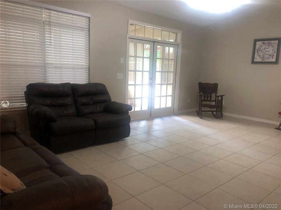 Spacious Living room, tiled floor, wood blinds, french doors to porch, ceiling fan & vaulted ceilings.