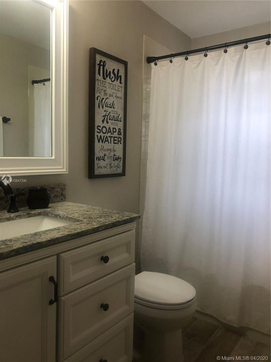 Bathroom 2, granite sink top and wood framed mirror