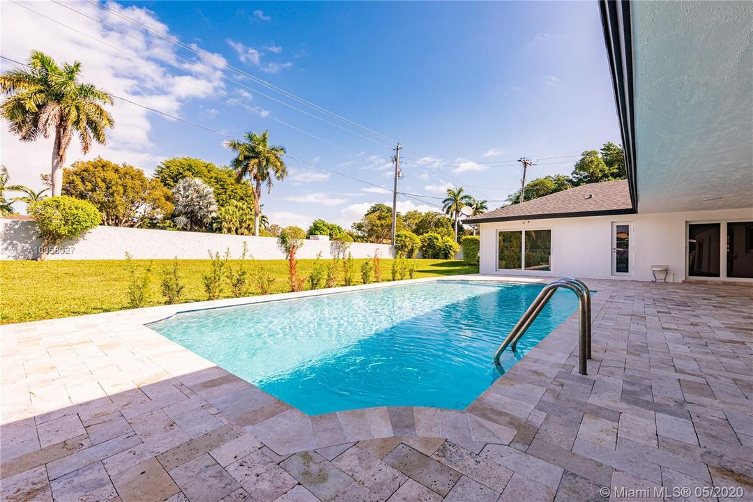 Completely renovated home showcases sparkling pool with covered terrace ideal for entertaining.