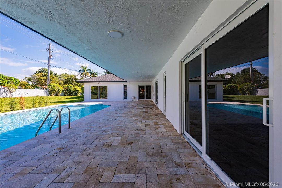 Covered terrace spanning the length of the house. Marble paver patio surrounding beautiful pool.