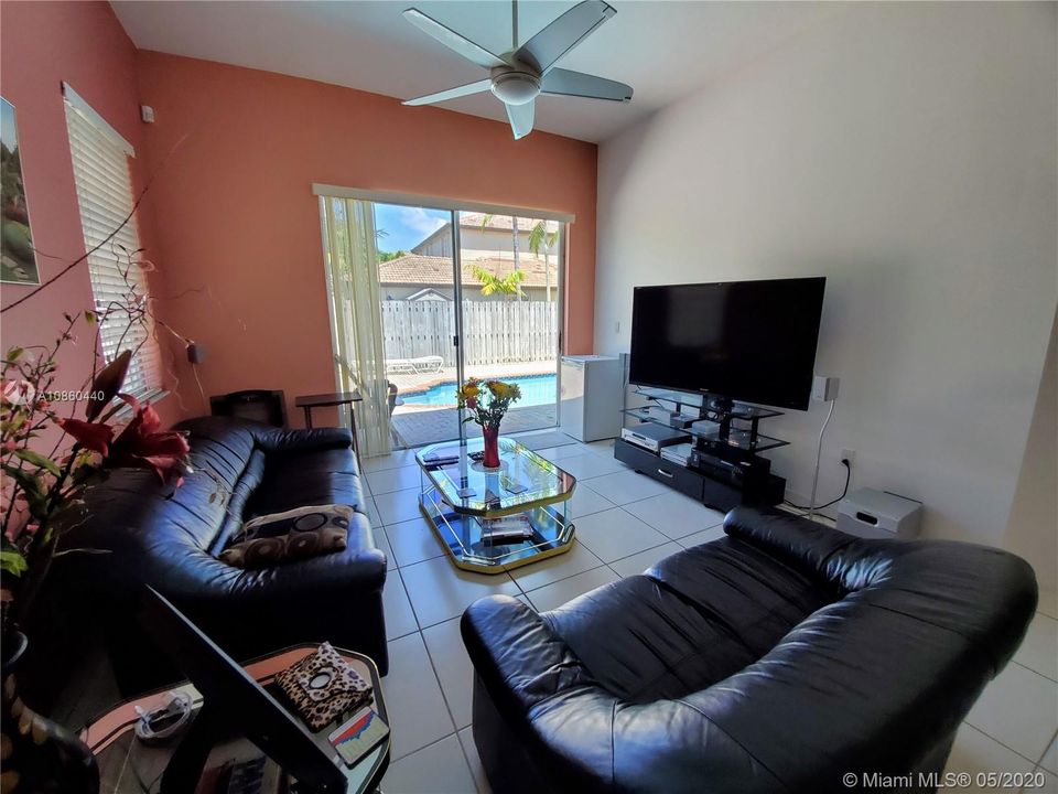 Family room has ceiling fan and overlooks outside pool area