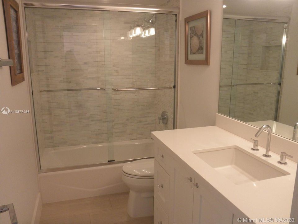 GUEST BATH HAS CUSTOM WHITE CABINET, QUARTZ COUNTERAND MARBLE AND GLASS WET WALLS