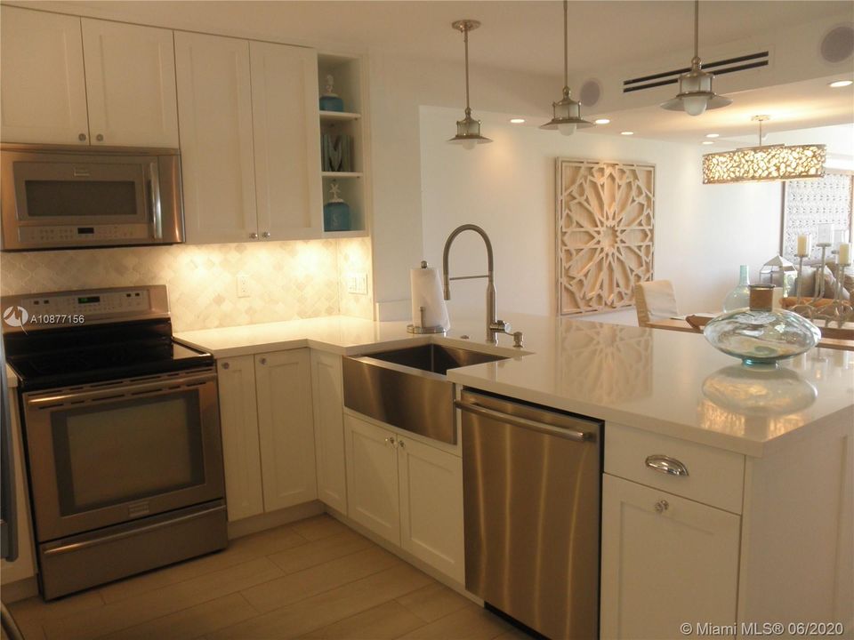 UPON ENTERING THE TOWNHOUSE YOU HAVE THE KITCHEN WITH CUSTOM WHITE WOOD CABINETS, STAINLESS APPLIANCES AND QUARTZ CABINETS