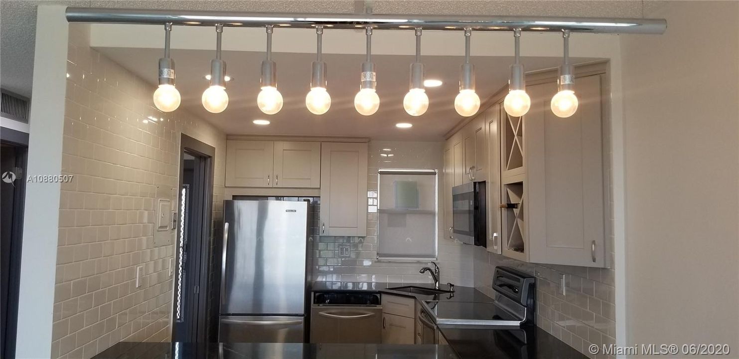 view of kitchen from counter seating of new subway tiles stainless steel appliance and undermount stainless sink