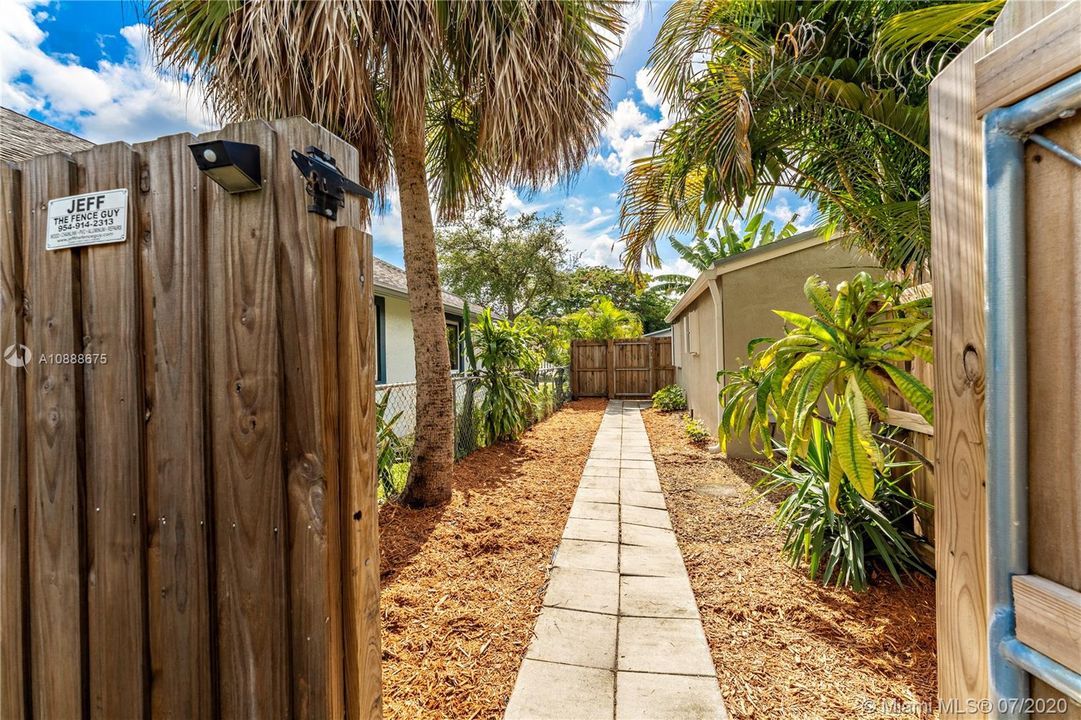 Fence that separates main house from guest cottage. Walk way facing east, main house in foreground.