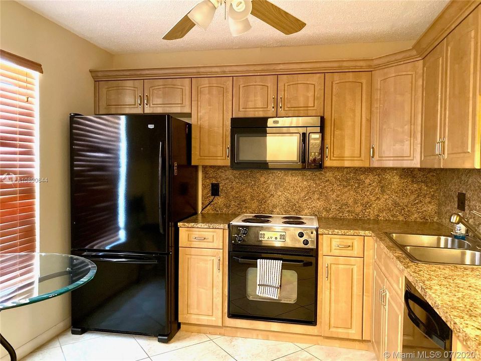 WOOD CABINETS WITH CROWN MOULDING AND EAT IN KITCHEN AREA.
