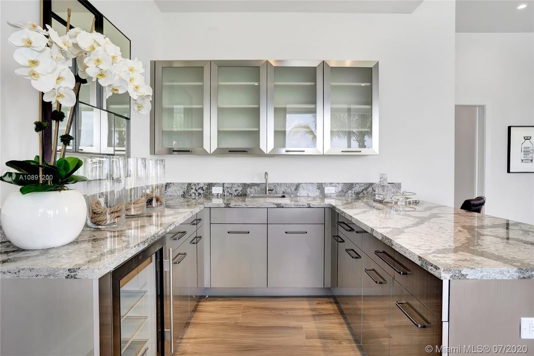 Bar features under counter refrigerator. Stainless steel sink and faucet. Quartz countertops.