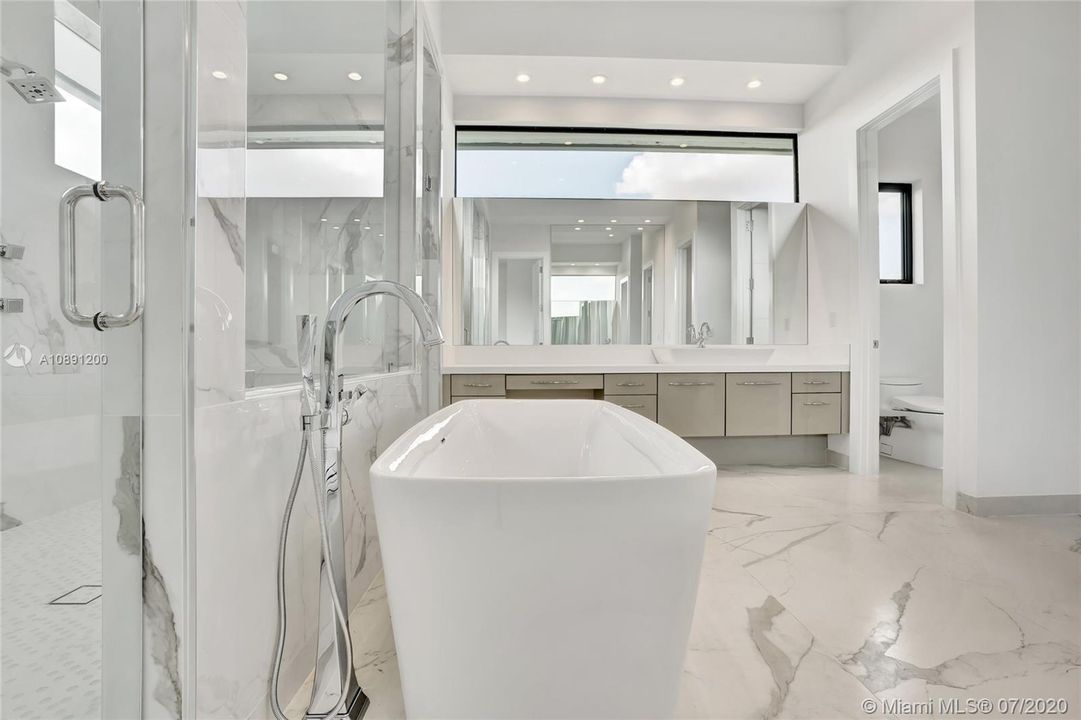 Luxurious marble primary bath with vessel tub and expansive his/her shower