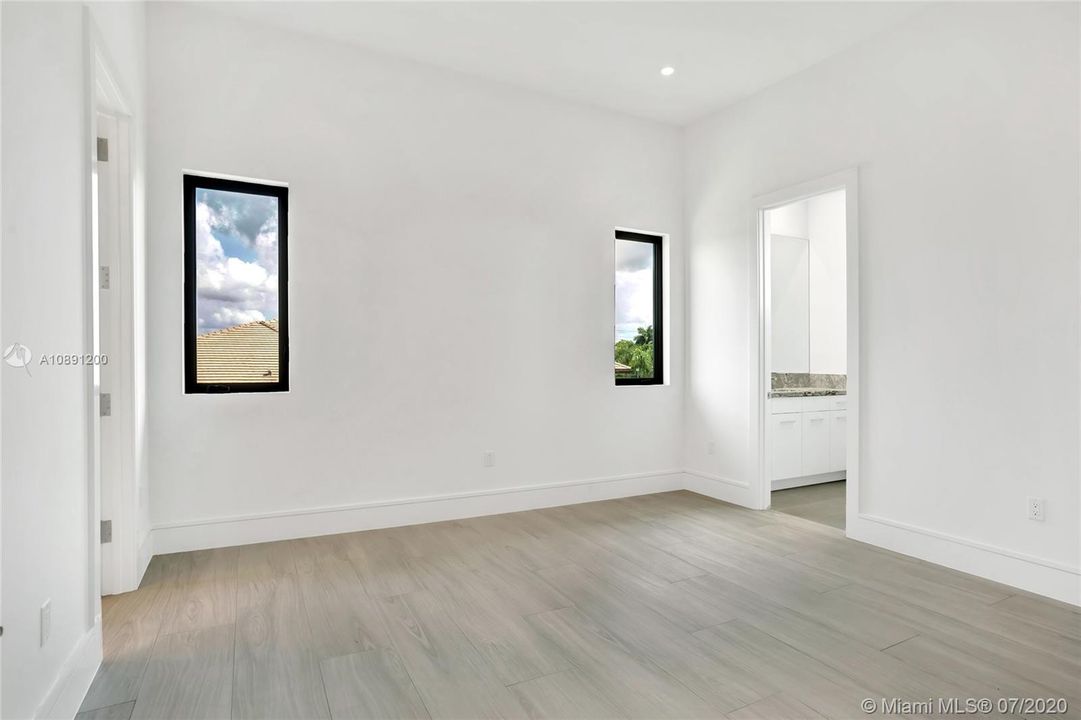 Secondary bedroom ensuite with walk in closed and wood flooring.