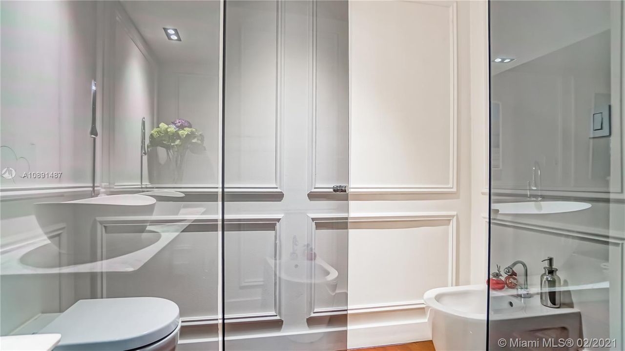Master bathroom water closet,  sleek dark grey glass door frames.