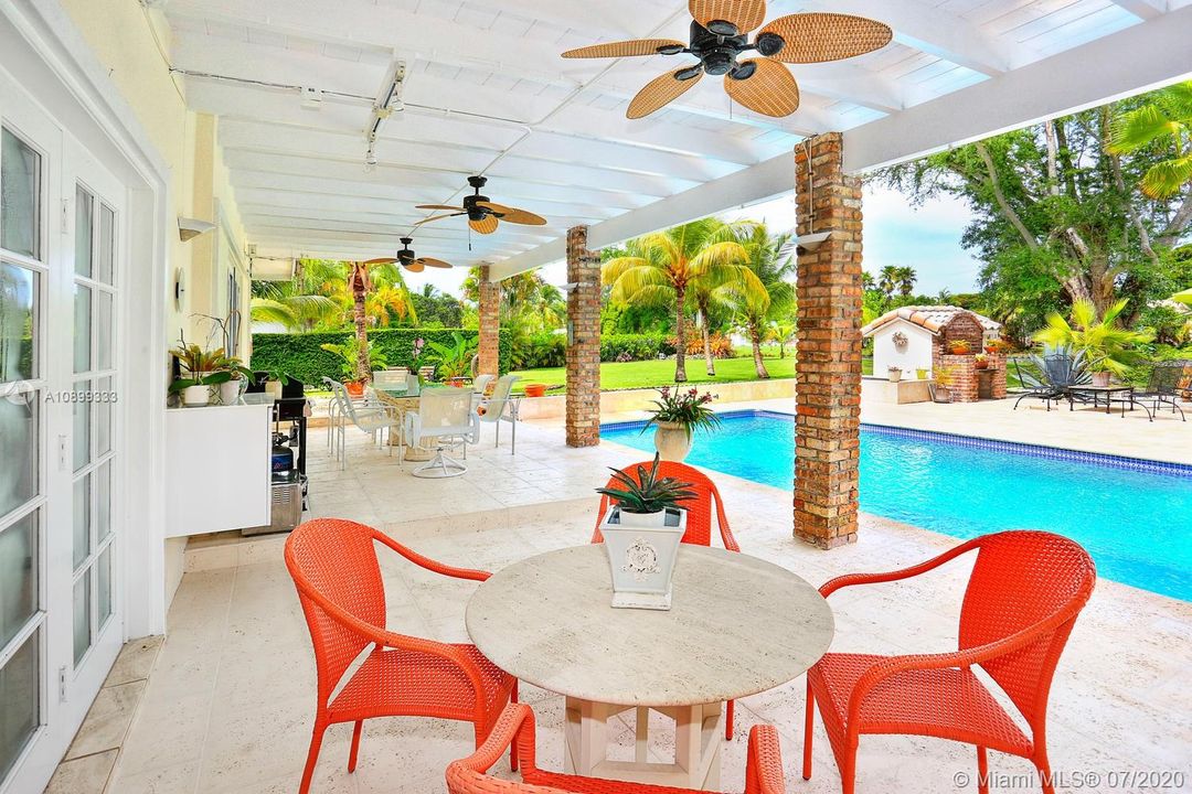 A comfortable cool patio are adjacent to a beautiful pool and yard.