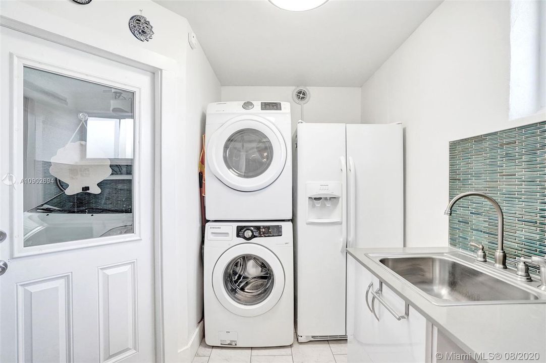 Utility/laundry room with sink, washer/dryer, and extra refrigerator/freezer.