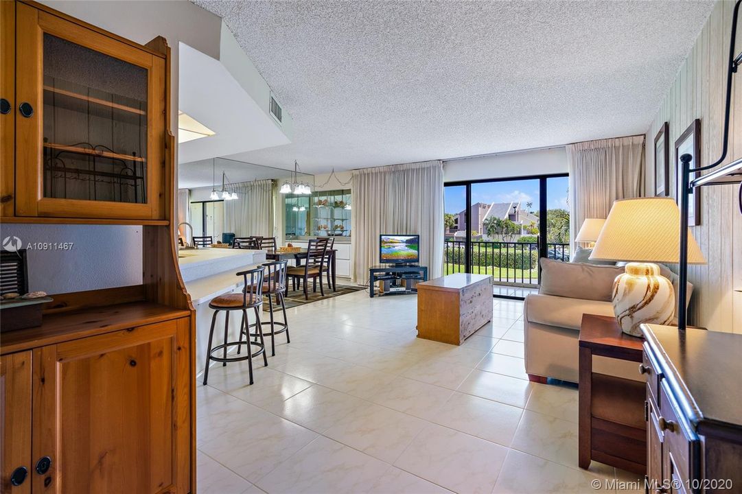 Open concept living room/ dining room /kitchen with tile flooring. Slider doors opens to open balcony/porch with storage closet.