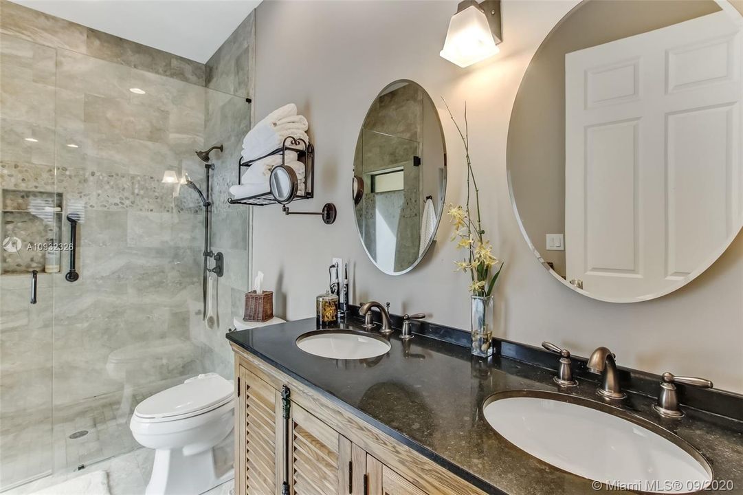 Master bathroom in guest house has dual sinks, large shower with frameless glass door, beautiful finishes and a separate door leading from the bathroom to the pool and patio.