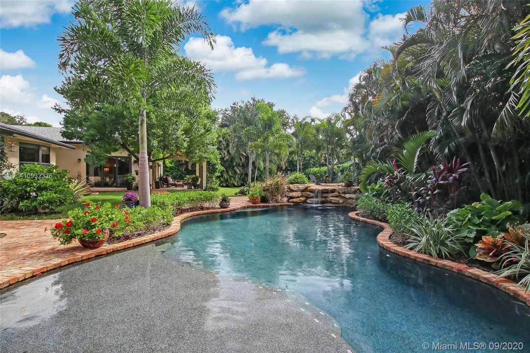 Custom free form pool with upgraded Pebble Tec surface, Intellichlor salt generator, rock wall and waterfall enhanced with a 90 square foot sun deck, professional landscaping and accent lighting.