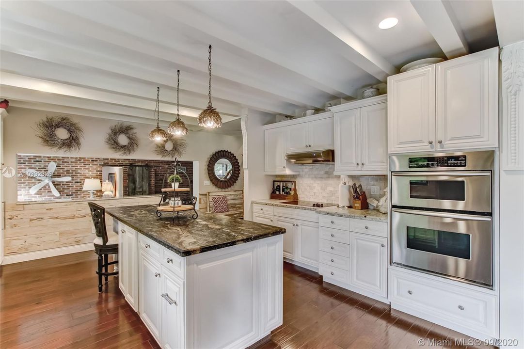 Granite countertops, basket weave marble backsplash and wood beams add so much charm to this incredibly spacious kitchen.