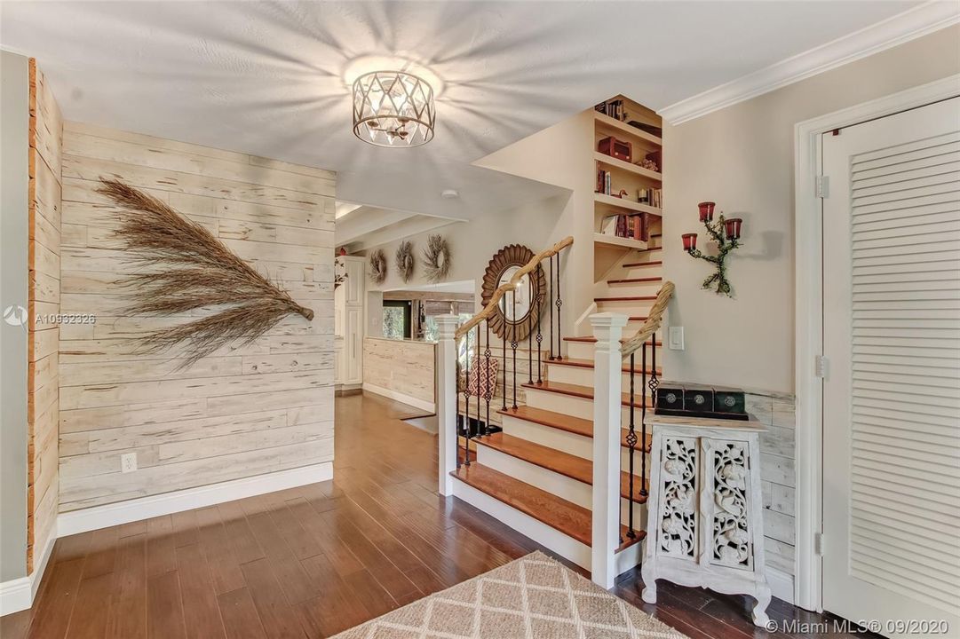 Foyer walls accented with unique Pecky Cypress paneling.  Note: Custom stair railing was added in 2019.