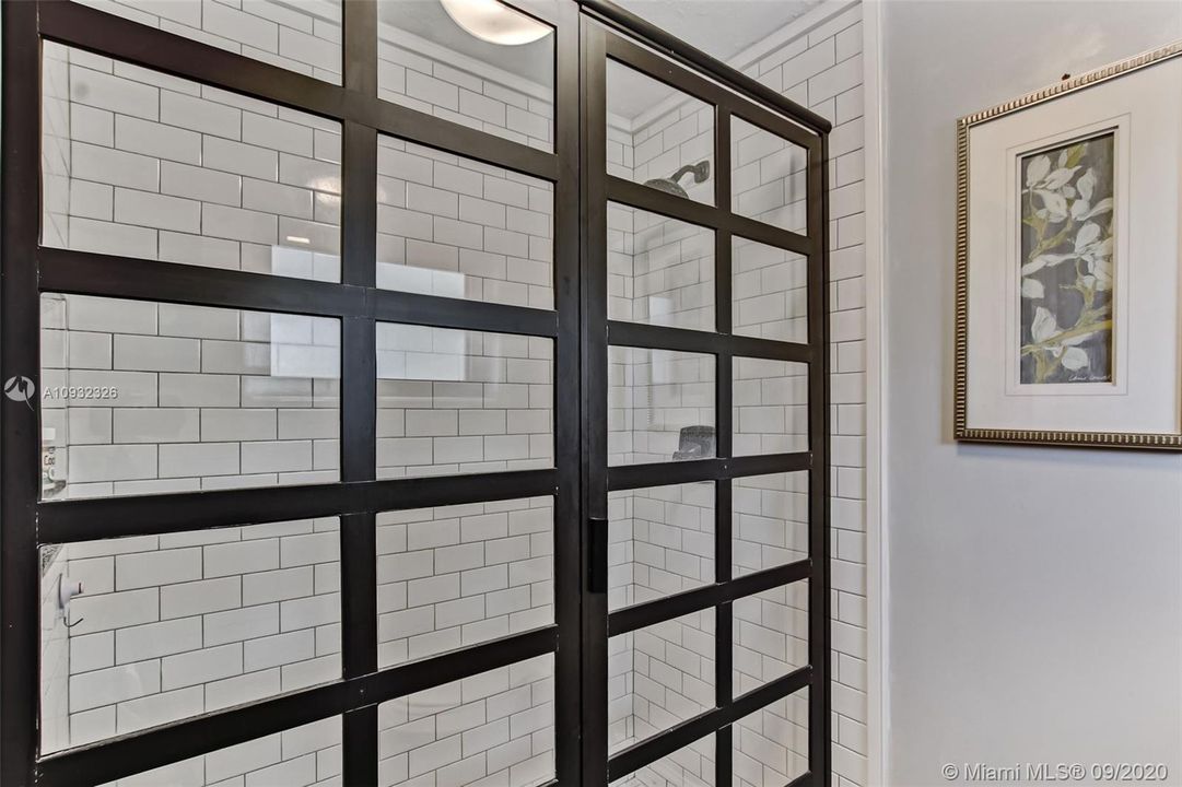 Upstairs hall bathroom is enhanced with custom industrial shower doors and subway tile.