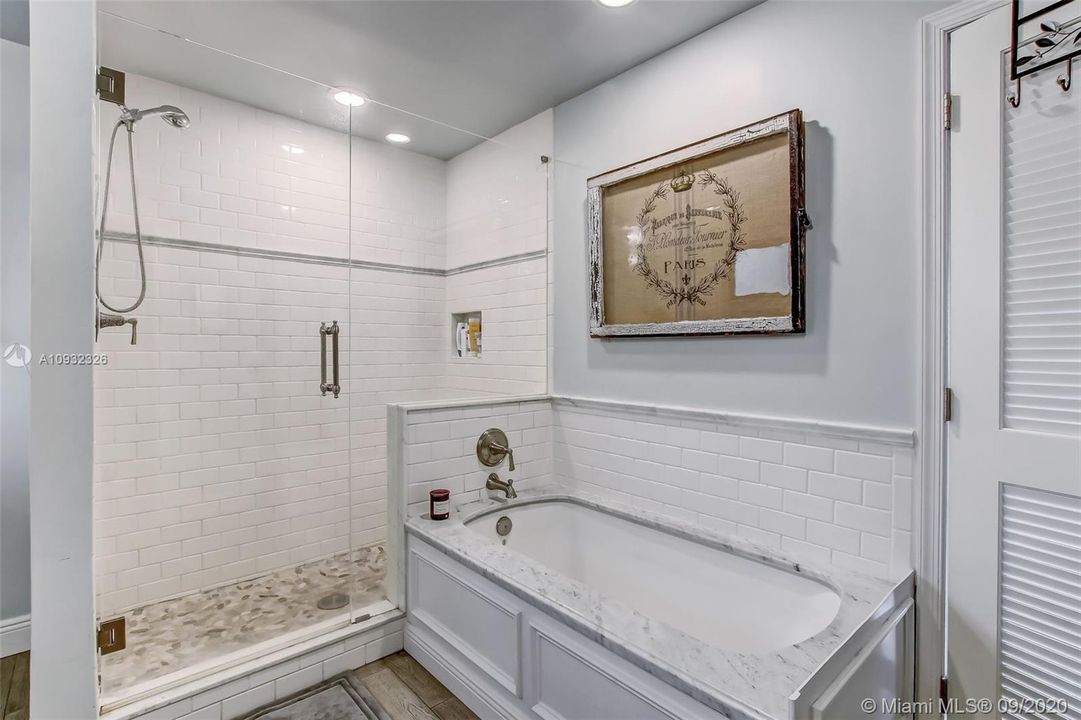 Master Bathroom with new commode, tub and shower with subway tile walls and frameless glass shower doors.