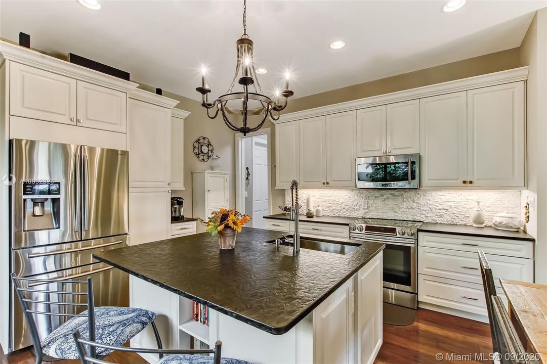 Guest house kitchen with leathered granite countertops and stainless steel appliances.