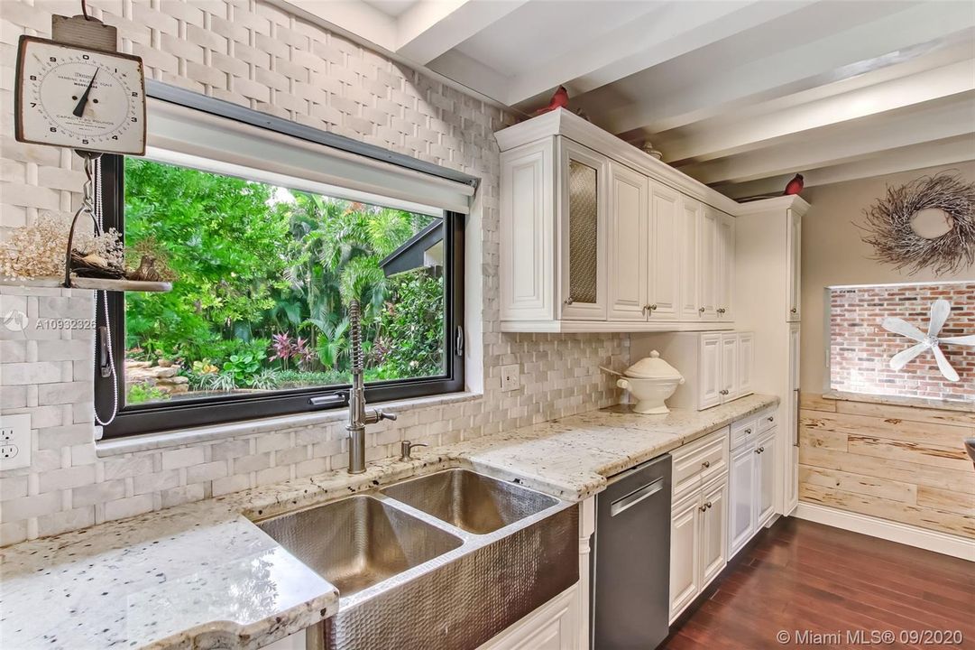 Completely remodeled kitchen with extensive cabinetry and pull-out drawers.  Kitchen features a coffee cabinet and built-in pantry.  The large, brushed hammered nickel farm sink has an upgraded faucet and the basket weave marble backsplash frames in this amazing kitchen.