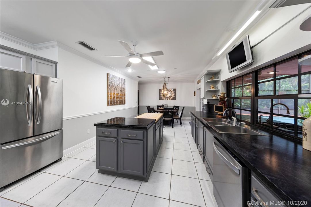 HUGE KITCHEN W/ CUSTOM CABINETS, COOKING ISLAND, STAINLESS STEEL APPLIANCES, AND EAT-IN AREA WITH FRENCH DOORS LEADING TO THE POOL.