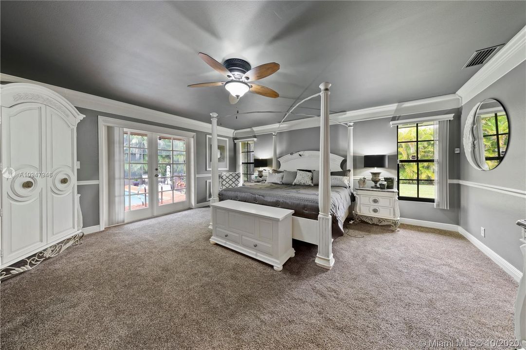 MAIN BEDROOM SUITE W/ FRENCH DOORS LEADING TO THE POOL.