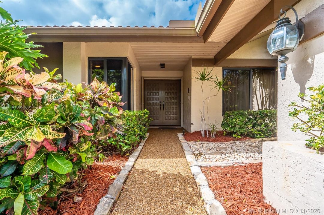 Private covered entrance with lush landscaping