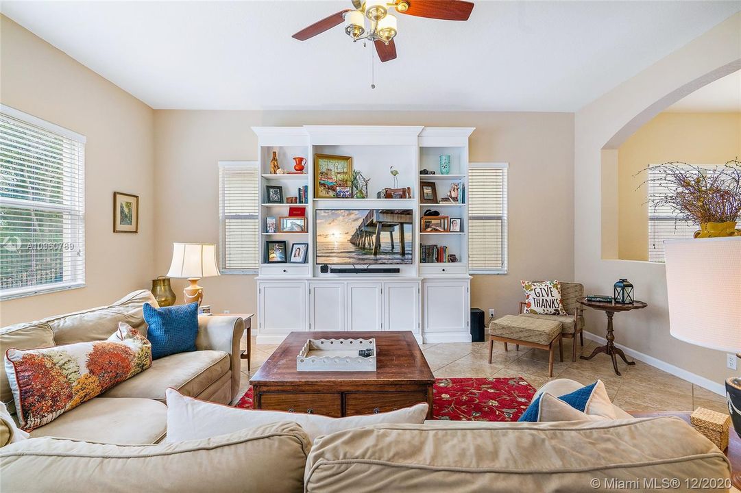 Family room with ceramic tile floors and wood blinds. 10' ceiling on first floor. TV cabinet is furniture, not attached and does not convey. Approximate 16x19