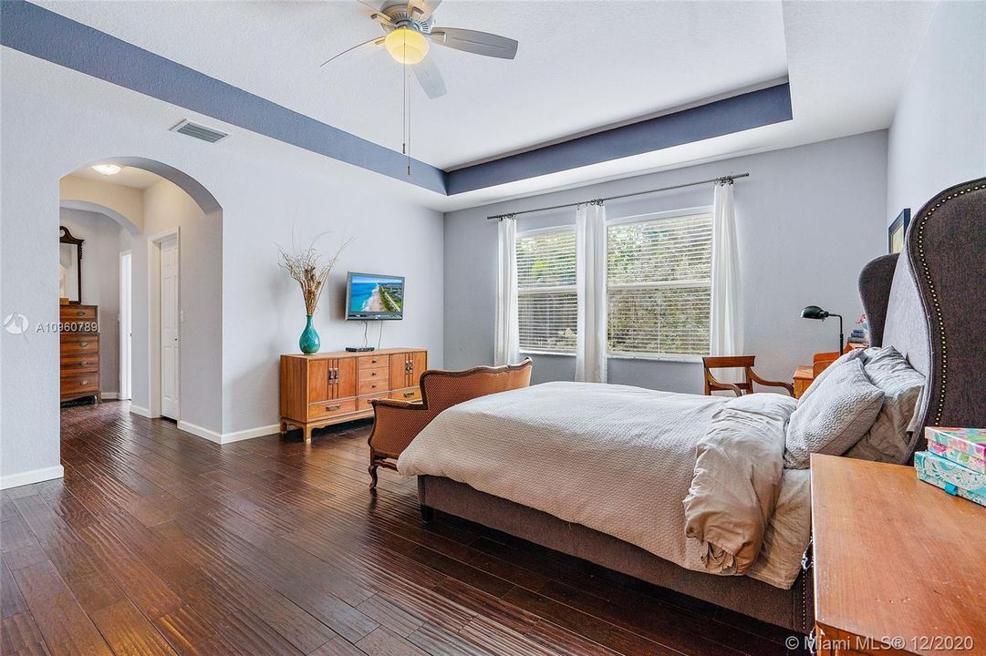 Master suite with wood floors and wood blinds, 2 walk-in closets and dual bathrooms with adjoining walk thru shower. Coffered ceiling.