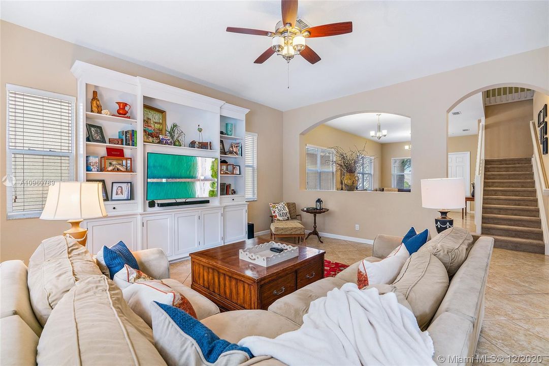 Family room with ceramic tile floors and wood blinds. 10' ceiling on first floor. TV cabinet is furniture, not attached and does not convey.