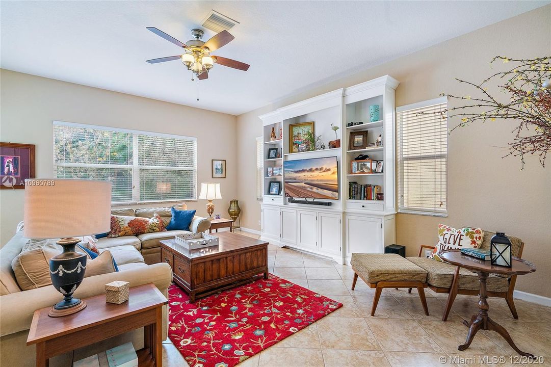Family room with ceramic tile floors and wood blinds. 10' ceiling on first floor. TV cabinet is furniture, not attached and does not convey.