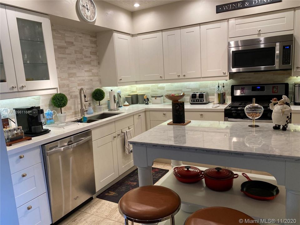 Beautiful light kitchen with tile and backsplash throughout, stainless steel appliances, Williams Sonoma island with marble top.