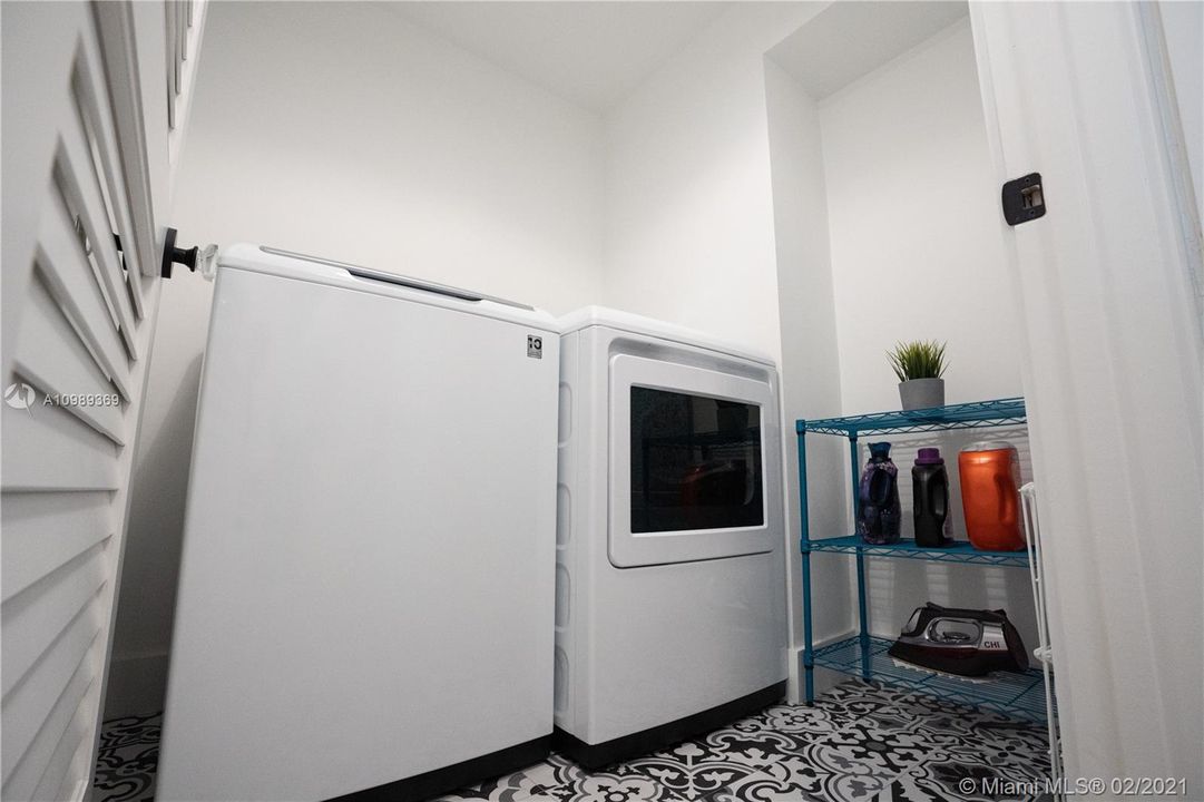 Desiganted Laundry room area that showcases Porcelanosa tiles, vented door including trim combined glass doorknobs and equiped with Extra Large capacity washer and dryer
