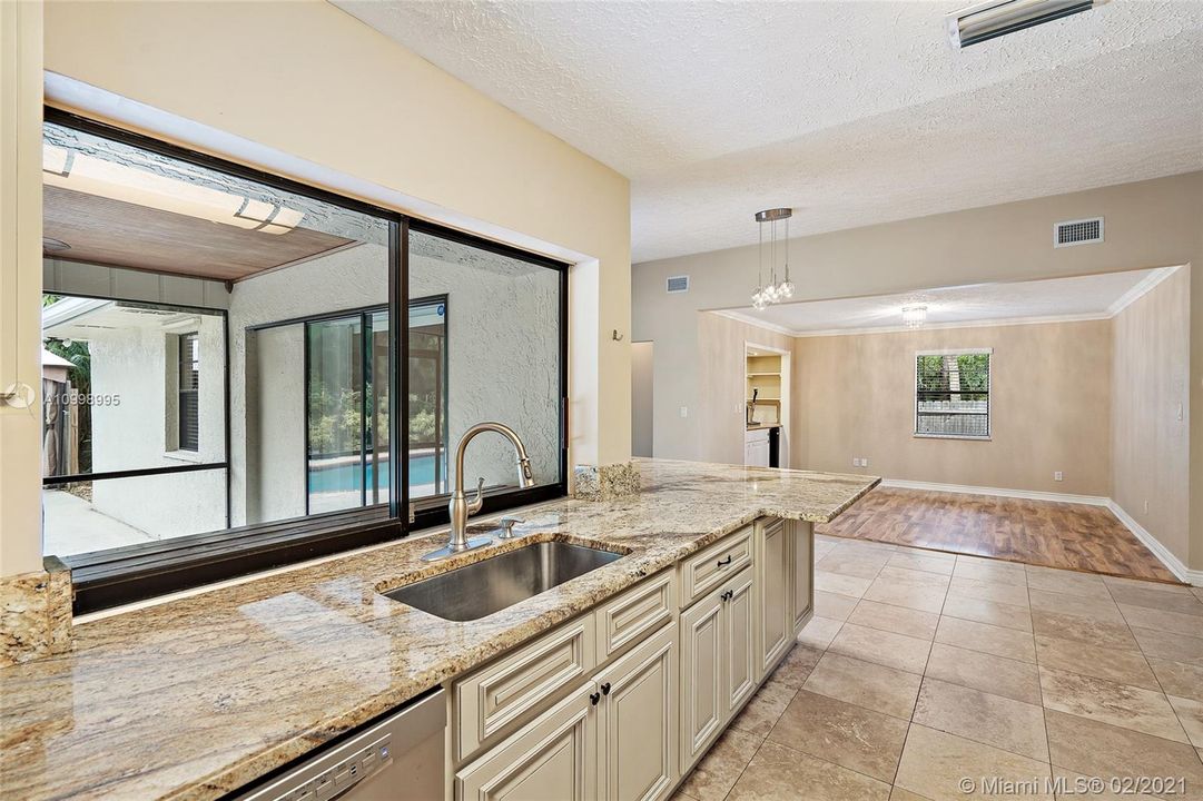 Kitchen with sliding glass window pass through to screeened in lanai.