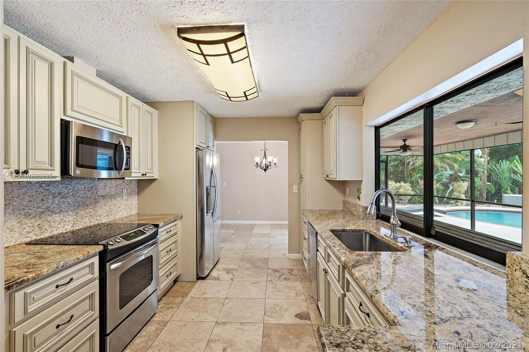 Kitchen with sliding glass window pass through to screeened in lanai.