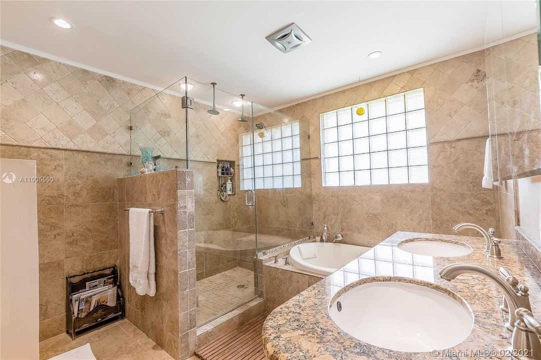 Main bathroom with jacuzzi tub, stall shower and double sinks.