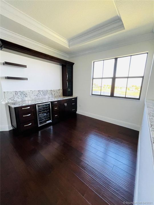 Master bedroom has upgraded sitting area. This particular space includes granite countertops, wine cooler, sink, and plenty of space for storage.