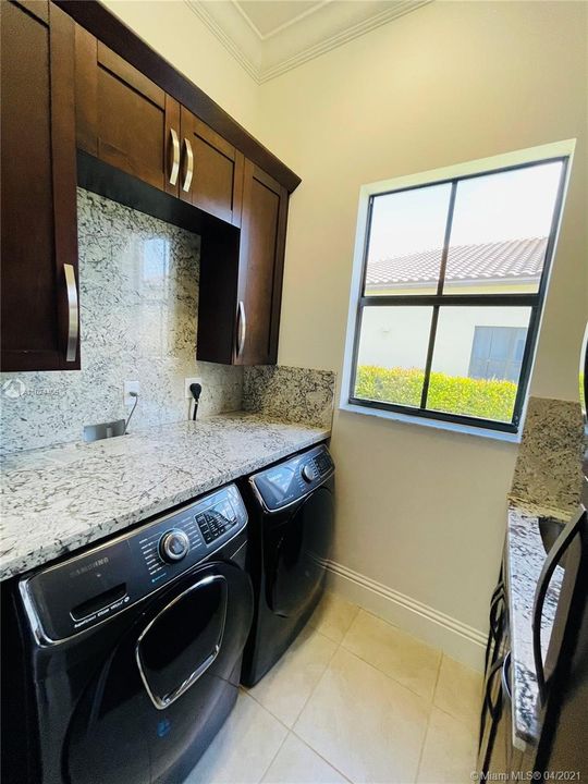 Laundry room includes upgraded washer and dryer and upgraded cabinet space with a sink.