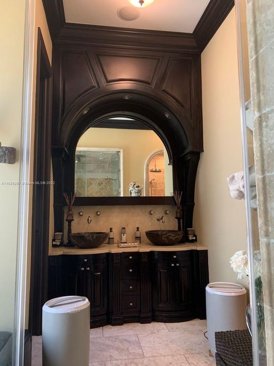 Cabana bathroom vanity with TV behind 2 way mirror and 2 marble bowl sinks and wall faucet handles
