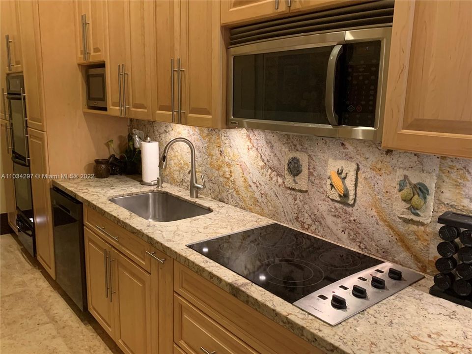 Cabana kitchen with granite countertop and backsplash with cabinets almost to ceiling (12 ft). Electric stovetop and 2 microwave ovens and Double oven  with bottom bread warmer
