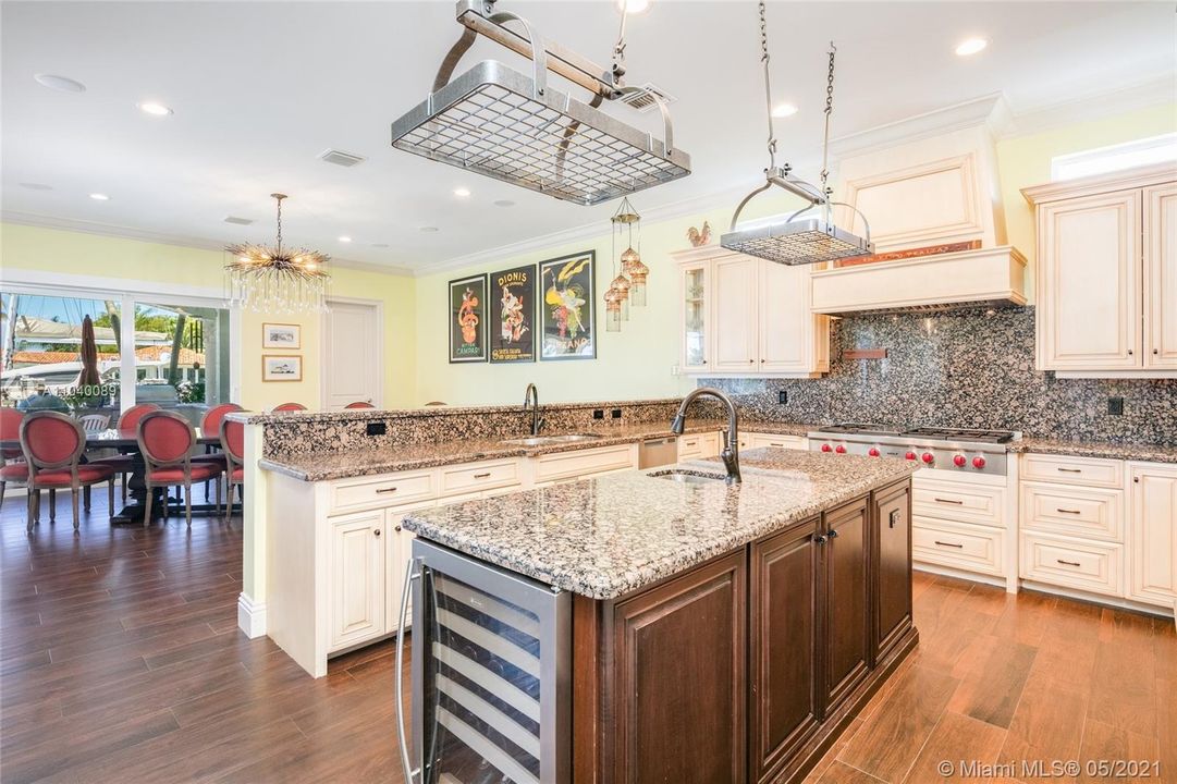 Gourmet kitchen featuring granite countertops, wine cooler, gas range & stainless steel Wolf appliances.