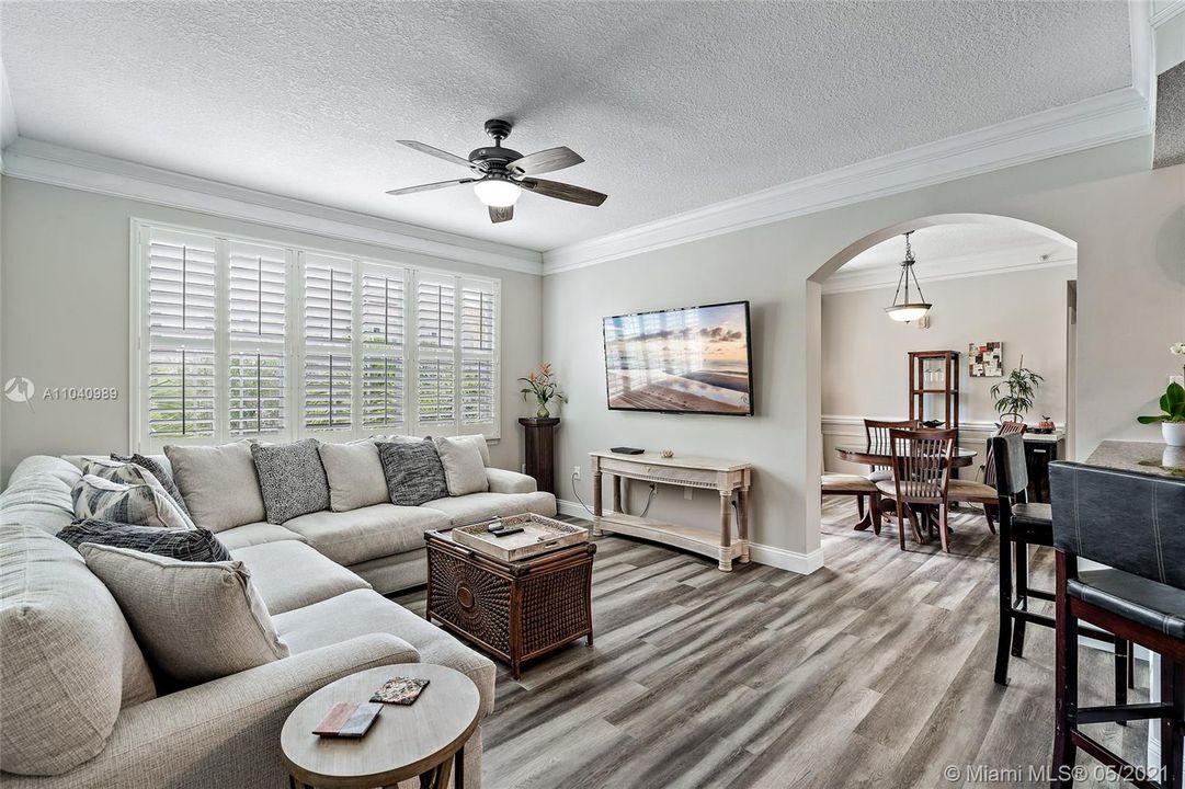 Living room  with plantation shutters open to kitchen and dining room.