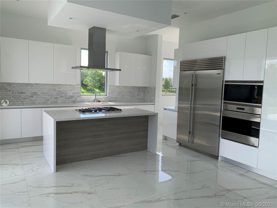 Italian cabinetry, white quartz waterfall island  and High End Designer Kitchen Appliances